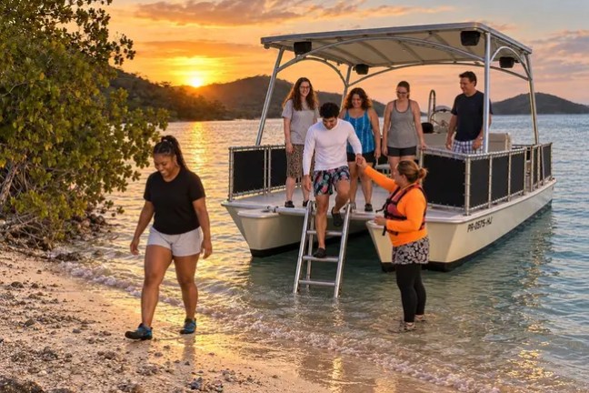 People disembark a pontoon boat at sunset on a beach with calm water.