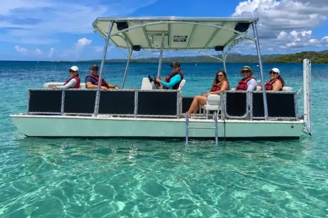 Group on a boat in clear turquoise water under a blue sky with clouds.