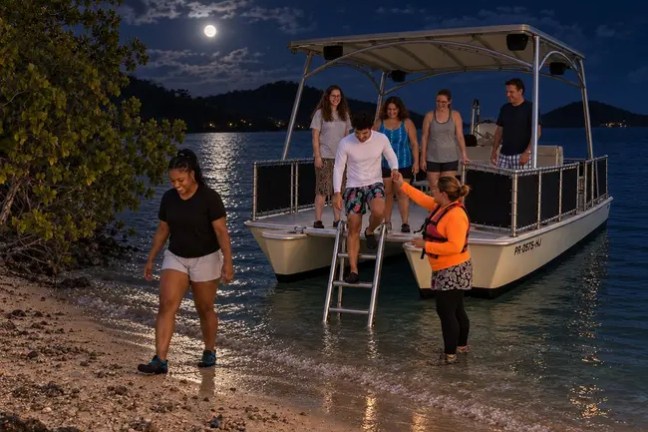 People disembarking a boat at night under a full moon.