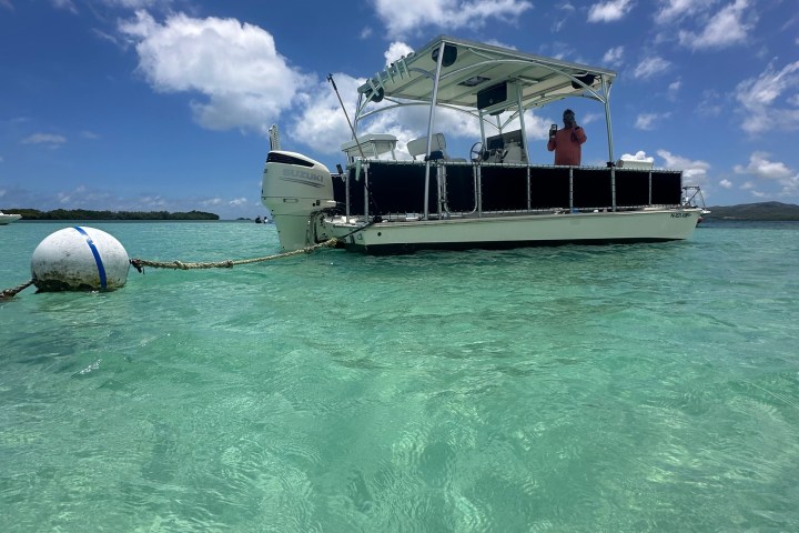 Boat anchored in clear turquoise water under a sunny sky.